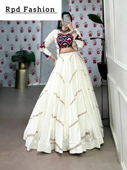 A woman in a flowing white cstands against a wall, emphasizing her elegant style and the dress's design - RPD Fashion