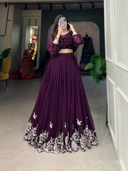 Person wearing a purple embroidered outfit in a room with mirrors and plants.