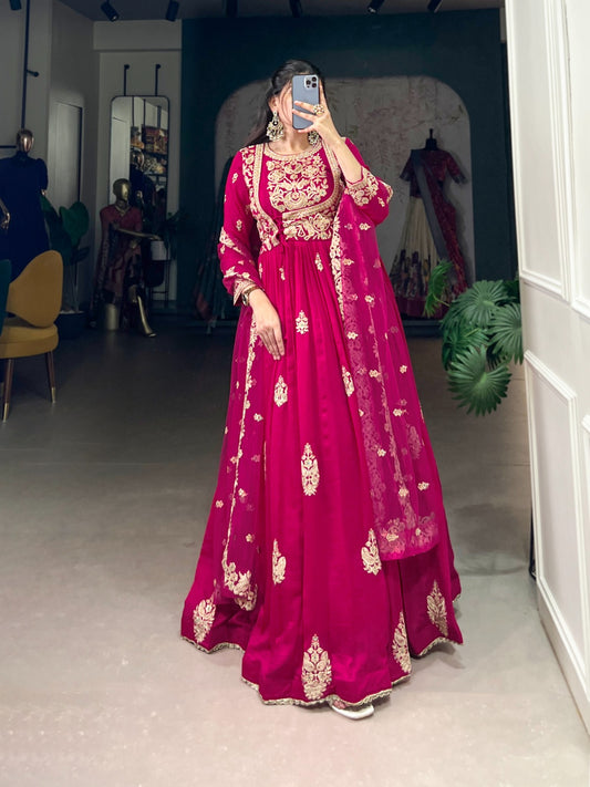 Person wearing a pink embroidered traditional outfit in a room with mirrors and furniture.