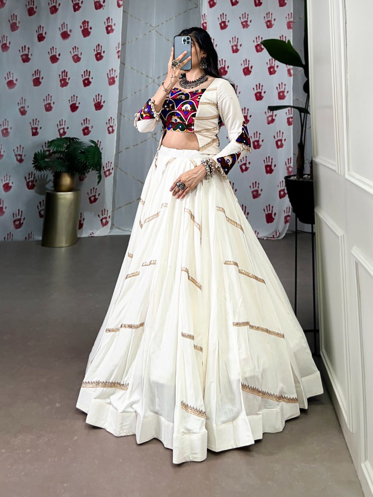 a woman in a flowing white cstands against a wall, emphasizing her elegant style and the dress's design rpd fashion