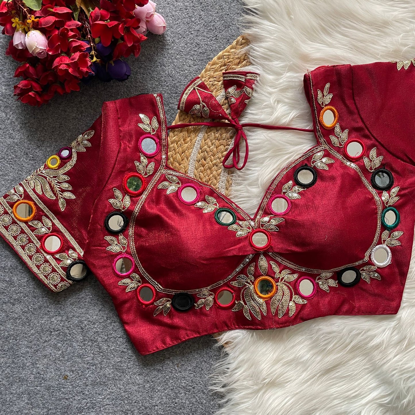 red embroidered blouse with colorful buttons on a textured surface with flowers.