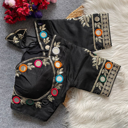 Black blouse with colorful mirror work on a textured surface with flowers