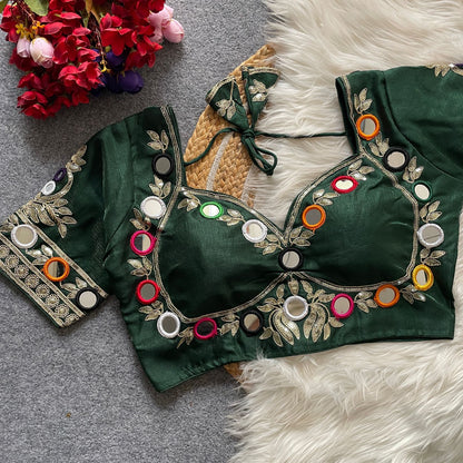 Green embroidered blouse with colorful buttons on a textured surface with flowers.
