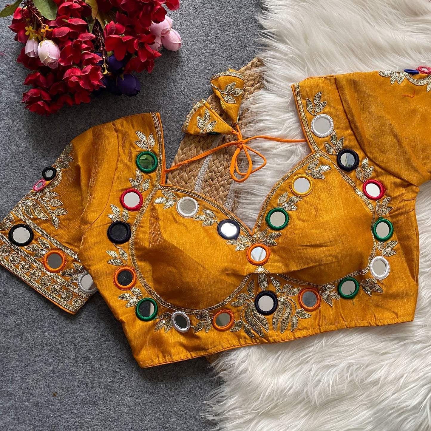 yellow embroidered blouse with colorful buttons on a textured surface with flowers.